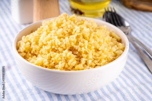 Foto Boiled cooked bulgur pilaf, healthy wheat garnish, side dish, in white ceramic p