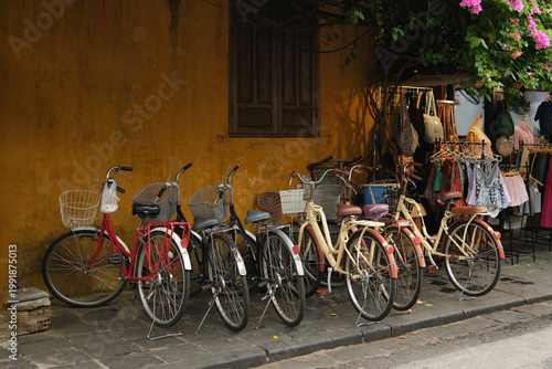 Fotografija Row of parked bicycles in a tourist area of Hue city, set against an orange buil