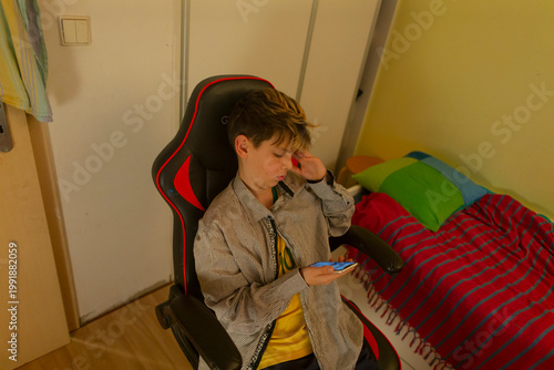 Teenager posing reacting to message on smartphone with subtle surprise, gaze fixed on screen intimate bedroom corner with soft light, shelf and bed visible, candid emotion captured