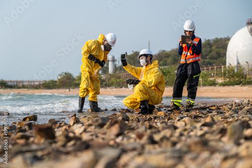 Obraz na płótnie Environmental scientists in protective hazmat suits collecting water samples for pollution analysis and ecological research at an industrial site