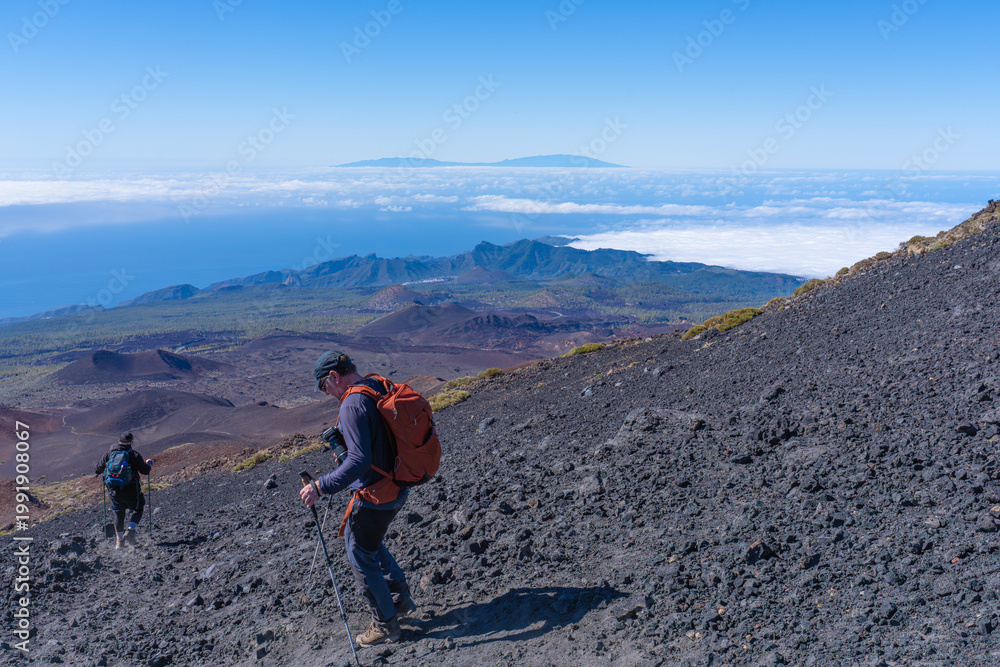 Fototapeta premium Tourists cross a lava field in Teide National Park.