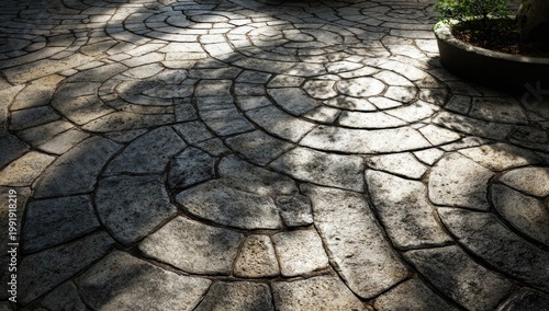Close-up of a cobblestone patio with a circular pattern and dappled sunlight