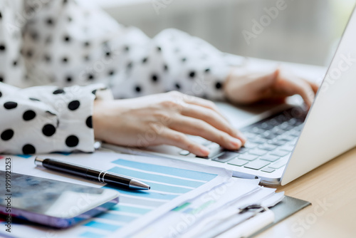 Smiling businesswoman working on laptop in café, enjoying hot drink, analyzing charts, planning projects, and staying connected in a modern professional lifestyle.

