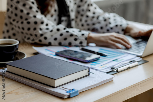 Smiling businesswoman working on laptop in café, enjoying hot drink, analyzing charts, planning projects, and staying connected in a modern professional lifestyle.

