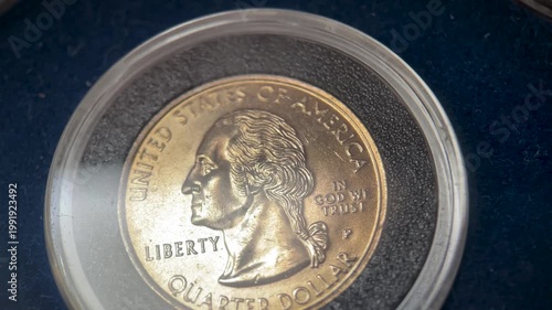 Close up video of a 1999 United States quarter dollar coin featuring the obverse portrait of George Washington, displayed inside a protective capsule.