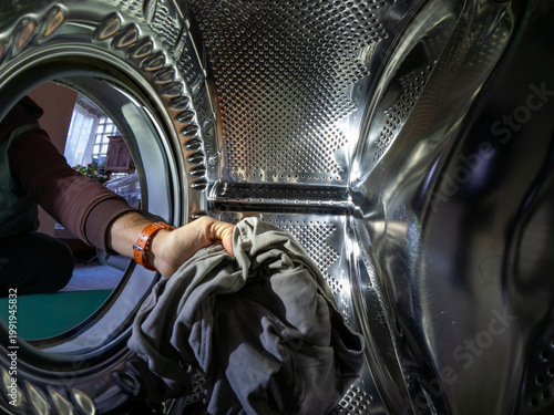 Man's Hand Putting Laundry into Washing Machine Drum, Inside View