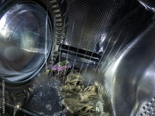 Inside View of Washing Machine Drum with Soap Foam and Wet Laundry