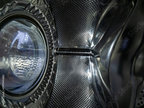 Inside View of Empty Chrome Washing Machine Drum with Water Drops