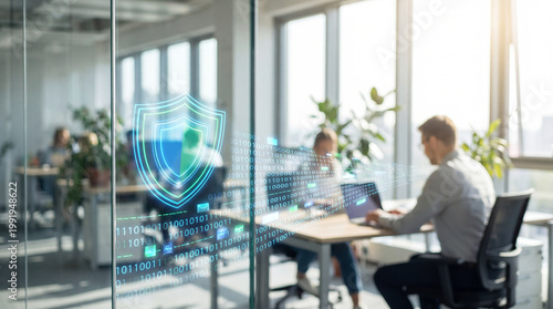 Modern office with two colleagues working at laptops behind glass, digital data stream and holographic shield overlay representing network security and data protection in bright workspace