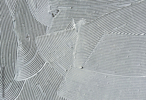 Gray tile glue surface with notched trowel lines