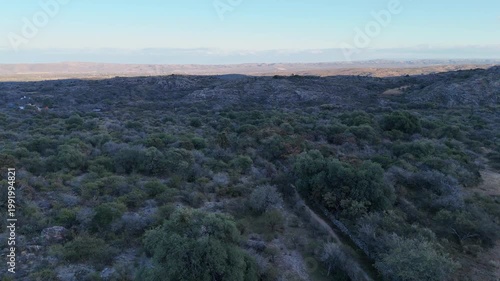 Trail runner training on a rocky mountain path in an arid landscape.