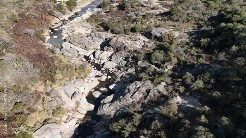 Trail runner training on a rocky mountain path in an arid landscape.