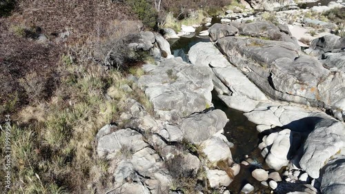 Trail runner training on a rocky mountain path in an arid landscape.