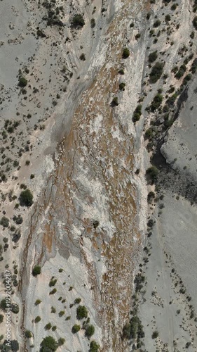 Dry riverbed with mineral formations and cracked mud in arid landscape under blue sky