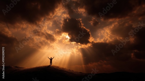 A person stands on a ridge with arms spread wide, bathed in the golden light of sunset.