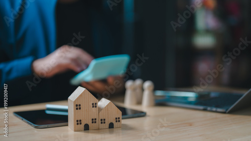 Tableau sur toile Professional businessman calculates mortgage costs utilizing wooden house models