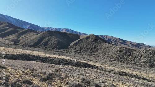 Aerial drone view of dry mountain landscape in San Juan Argentina under clear blue sky
