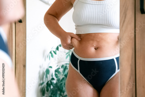 Woman overweight body. Female touching stomach near mirror. Weig