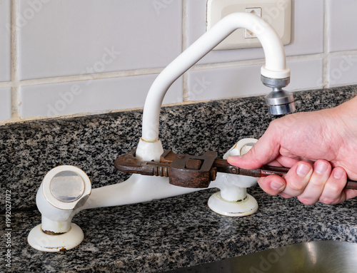 Man fixing an old a tap with a pipe wrench