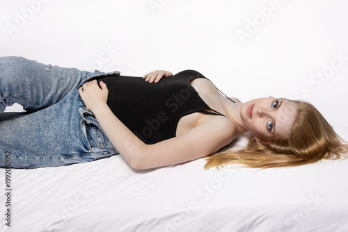 Side view od young pregnant woman lying on her back and looking at the camera. Horizontally. 