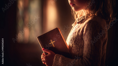 Little girl holding holy bible in church. Kid praying with sacred book in hands. Religious faith and spiritual devotion concept. Christian belief and worship during Easter or Christmas time.