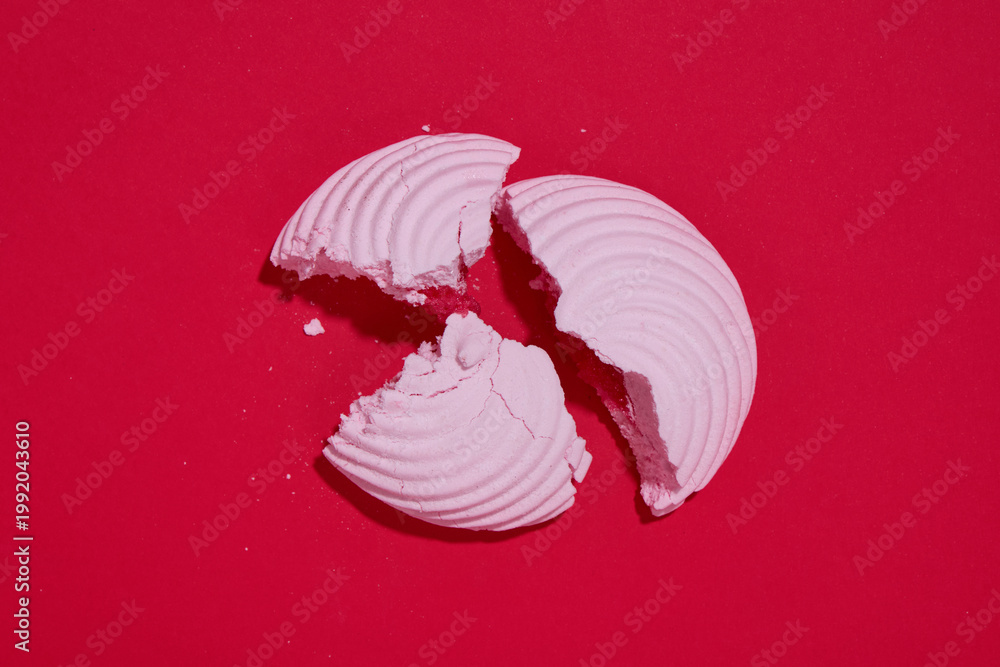 Fototapeta premium A piece of broken marshmallow on a red stylish background. Marshmallows with filling