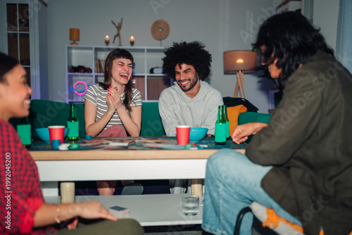Obraz na płótnie Diverse group of young adult friends playing a board game, drinking beverages, a
