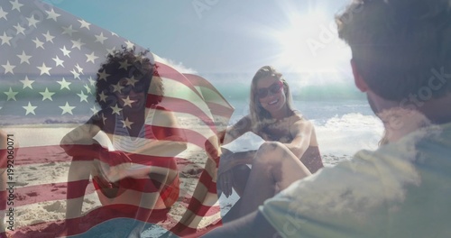 Sitting five friends chatting on beach, wearing swimwear and sunglasses with American flag overlay
