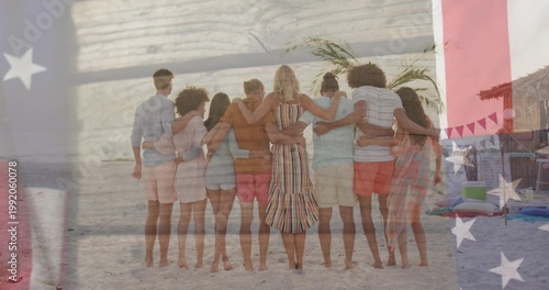 Standing eight adults linking arms on sandy beach, wearing center striped midi dress, flag overlay