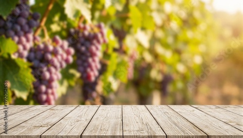 Empty light wood tabletop on a blurry vineyard background with purple grapes at golden hour. A warm surface for product display.