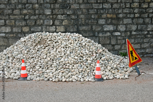 heap of stones with construction cones and roadwork warning sign