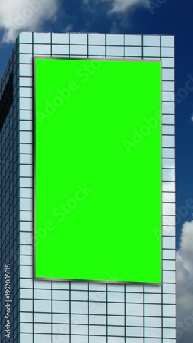 Green chroma key blank portrait billboard mock up in city center for advertising on office building skyscrapers with beautiful clouds background