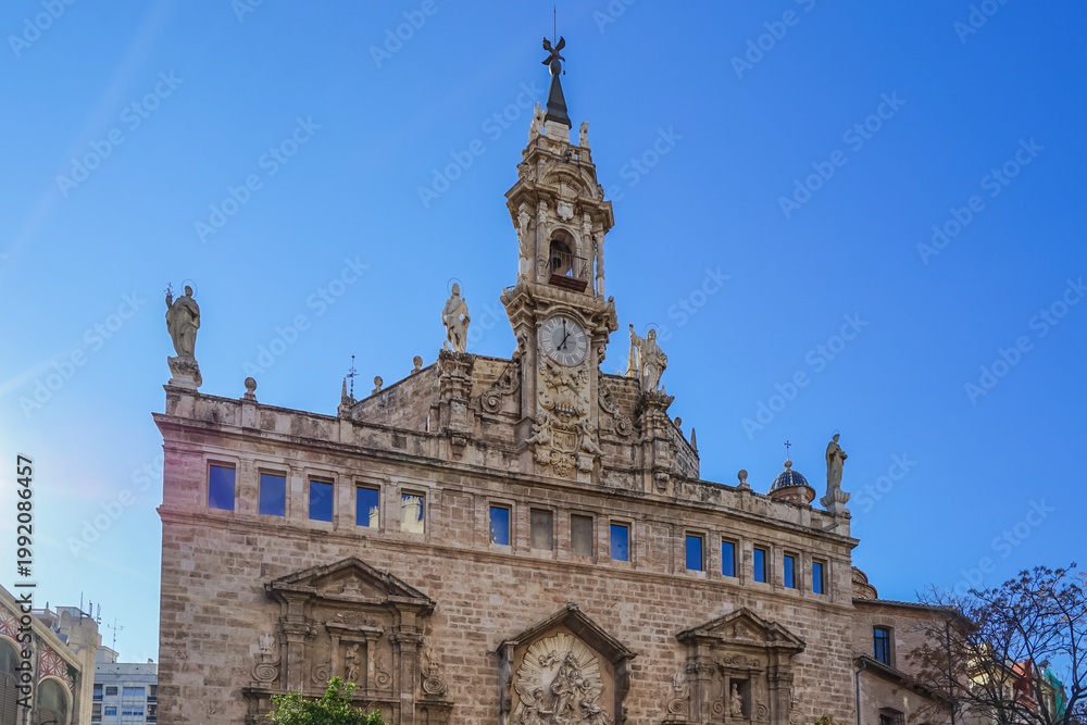 Fototapeta premium Ciutat Vella,Valencia,Spain,Historic stone church with ornate facade and bell tower under clear blue sky