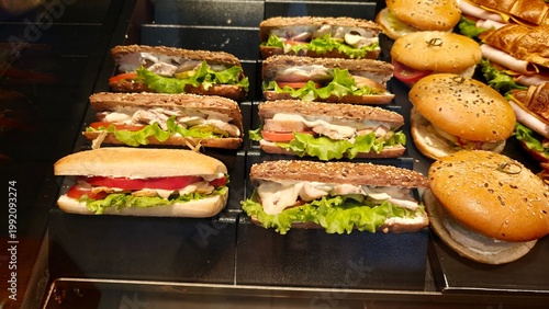 Fotografie Various sandwiches and buns displayed at a food counter in a busy restaurant