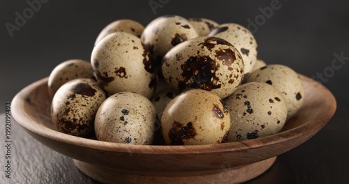 Quail eggs in a wooden bowl, close-up footage on a rotating table.