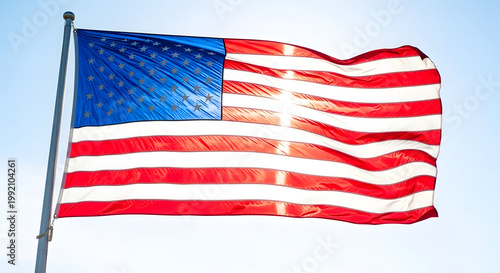 The American flag waving in the wind on a clear blue sky day on transparent background