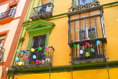 Balconies of a typical house in Seville decorated with multicolored paper lanterns for the April Fair (Feria de Abril). Seville Fair (Feria de Sevilla). Cheerful, joyful, colorful and fiesta.