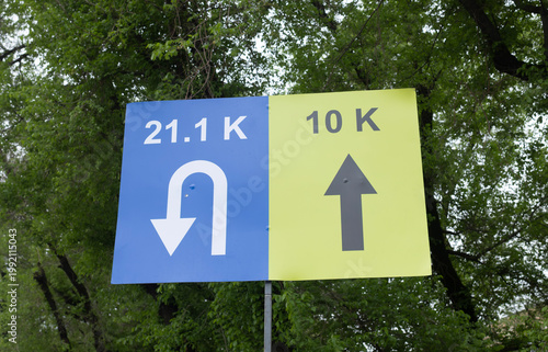 Road race distance direction signs 21.1K half marathon and 10K route arrow markers at running event