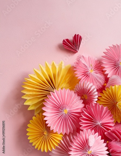 Close-up of bunch of origami paper pink and yellow daisies and pink heart origami on pale pink table on pale pink background with copy space
