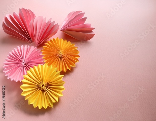 Close-up of bunch of origami paper pink and yellow daisies and pink heart origami on pale pink table on pale pink background with copy space