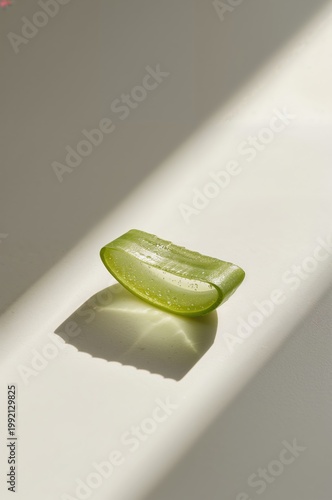 Fresh aloe vera slice glowing softly on white ceramic plate in daylight