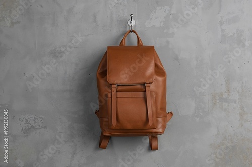 Minimalist tan leather backpack hangs quietly against textured concrete in modern urban style
