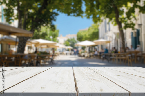 Empty white wooden table overlooking a blurred outdoor cafe
