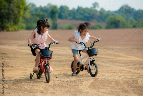 Принти на полотні Two Asian girls are having fun riding their bikes together during their holiday