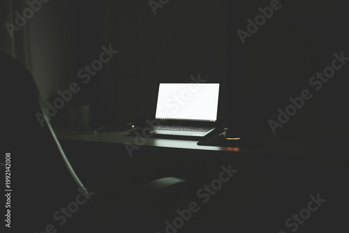 Dark workspace with laptop glow in moody light
