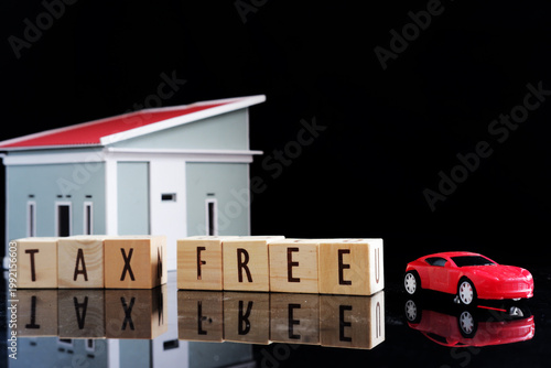 Miniature cars and miniature houses, with the words TAX FREE written on a dark background. Tax exemption with certain conditions.
