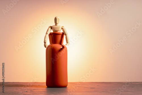 Wooden doll half emerging from red vase on orange background, escape and emergence concept