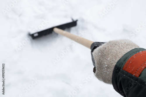 a hand in a knitted glove in perspective, clutching a shovel