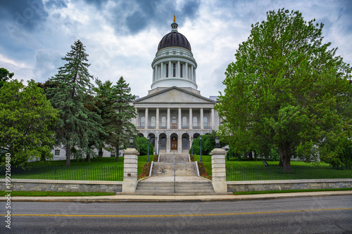 Maine State Capitol in Augusta, featuring neoclassical architecture, central dome, and landscaped grounds under a cloudy sky