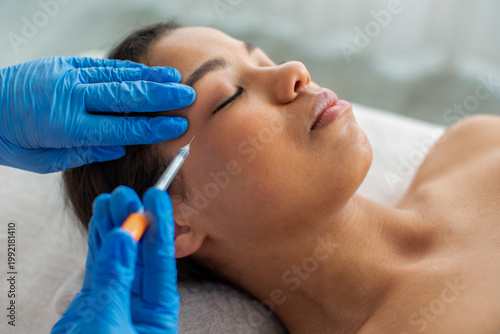 Foto Young African American woman lying relaxed while receiving facial injection trea